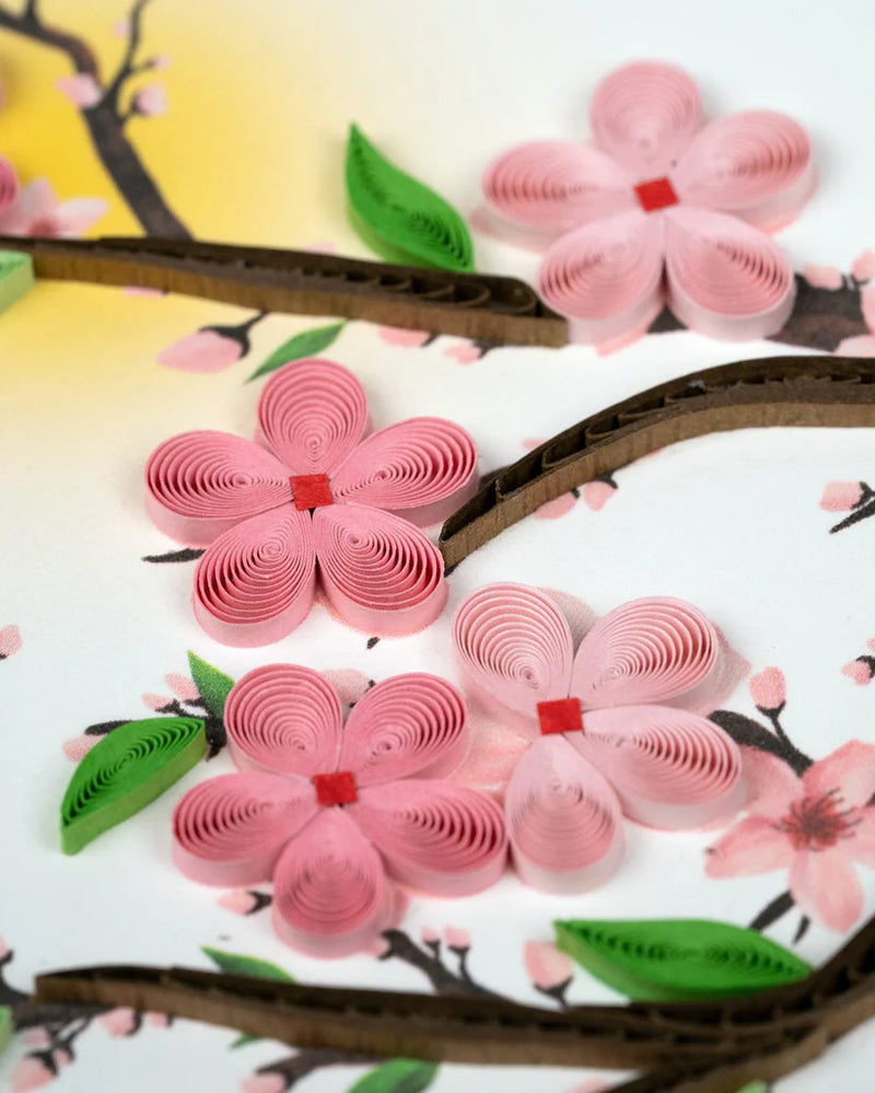 Handmade quilled card featuring pink cherry blossoms on tree branches, symbolizing renewal, spring, and beauty.