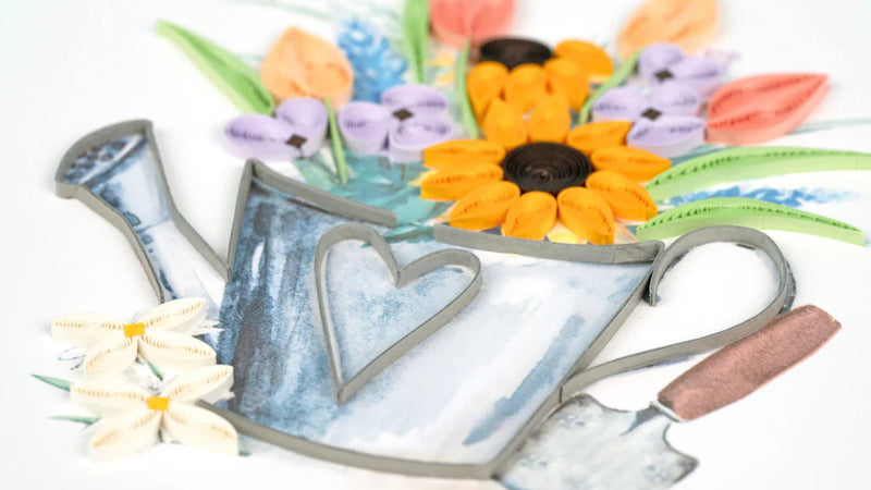 Quilled card with a silver watering can overflowing with colorful flowers, symbolizing joy and growth in a cheerful garden theme.