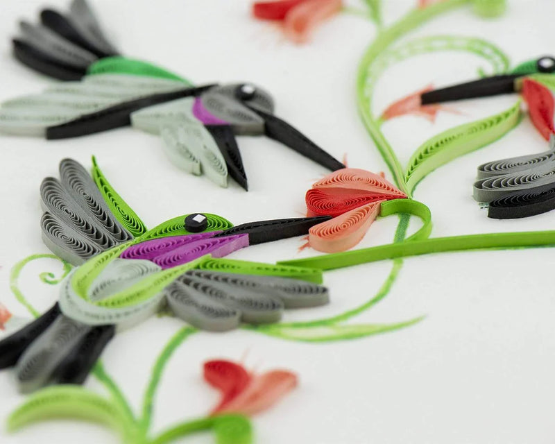 Quilled card with three hummingbirds flying around red flowers and green vines, symbolizing love, energy, and spiritual connection.
