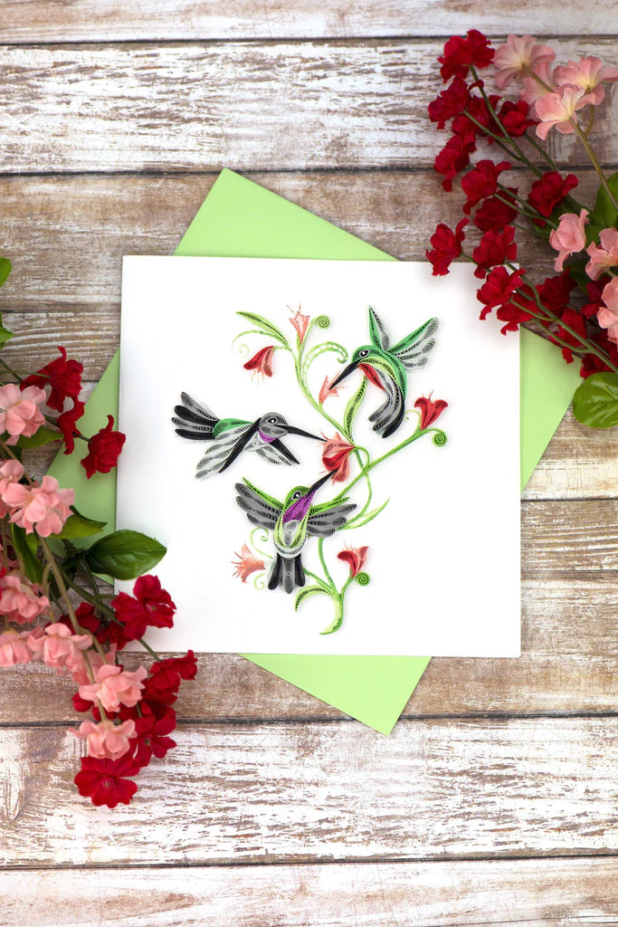 Quilled card with three hummingbirds flying around red flowers and green vines, symbolizing love, energy, and spiritual connection.
