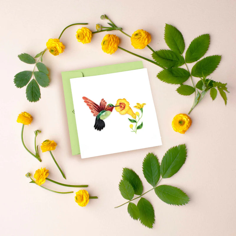 Handcrafted quilled card showing a hummingbird sipping nectar from vibrant yellow flowers, symbolizing beauty, energy, and joy.