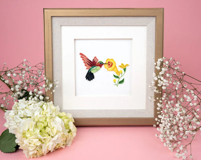 Handcrafted quilled card showing a hummingbird sipping nectar from vibrant yellow flowers, symbolizing beauty, energy, and joy.