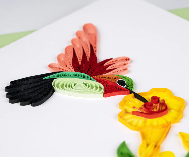 Handcrafted quilled card showing a hummingbird sipping nectar from vibrant yellow flowers, symbolizing beauty, energy, and joy.