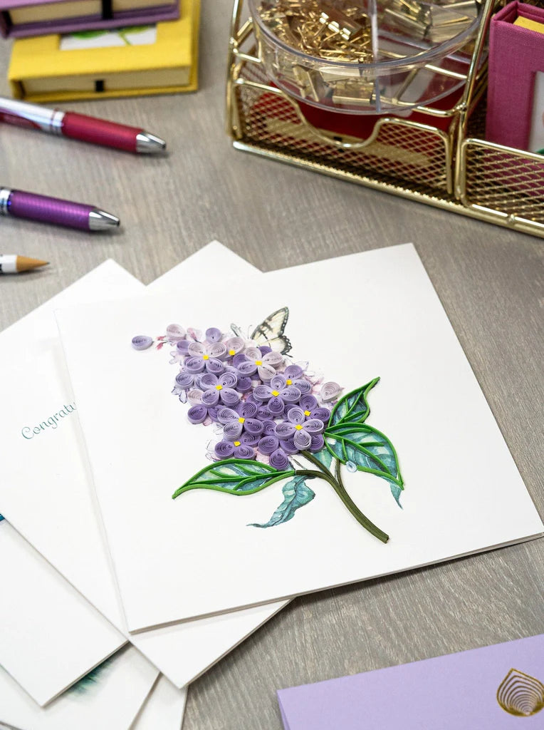 Quilled card with lilac flowers and green leaves on a watercolor background with a swallowtail butterfly