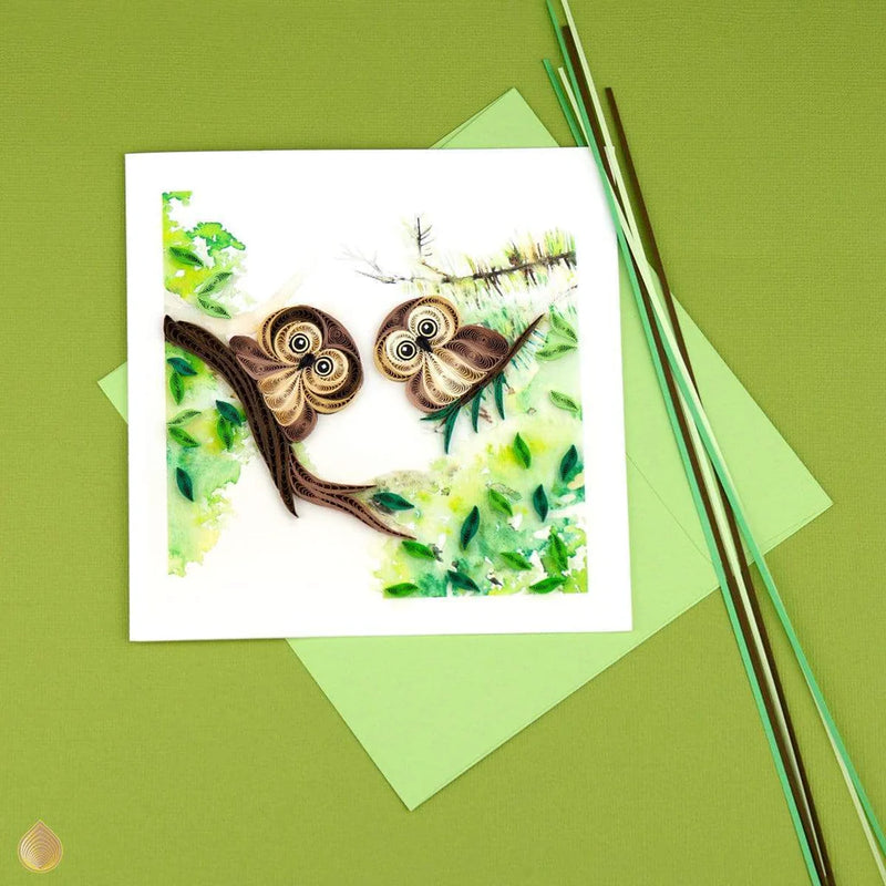 Quilled card with two brown owlets perched on leafy green branches, symbolizing wisdom, protection, and sweet friendship.