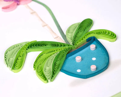 Handcrafted quilled greeting card featuring a pink orchid in full bloom, set in a blue polka dot pot with vibrant green leaves.