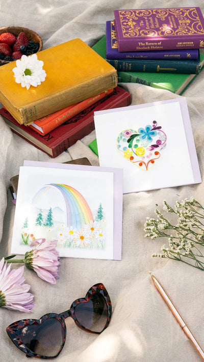 Quilled card with a rainbow arching over a mountain landscape and colorful flowers in the foreground. Symbol of hope and new beginnings.