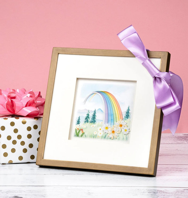Quilled card with a rainbow arching over a mountain landscape and colorful flowers in the foreground. Symbol of hope and new beginnings.