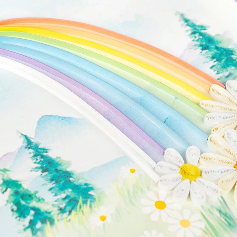 Quilled card with a rainbow arching over a mountain landscape and colorful flowers in the foreground. Symbol of hope and new beginnings.