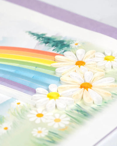Quilled card with a rainbow arching over a mountain landscape and colorful flowers in the foreground. Symbol of hope and new beginnings.