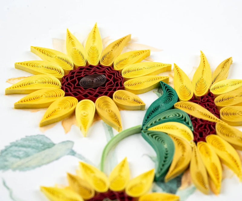 Hand-quilled greeting card featuring two blooming yellow sunflowers with green leaves, framed in soft yellow border on white background.