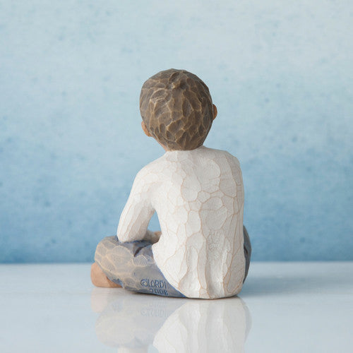 Willow Tree Imaginative Child figurine of seated boy with darker skin tone and hair.