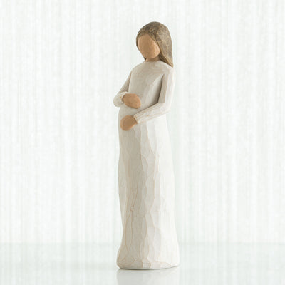 Willow Tree Cherish figurine of pregnant woman in cream dress with hands on belly.