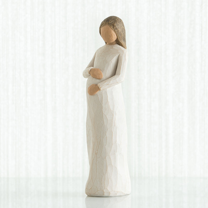 Willow Tree Cherish figurine of pregnant woman in cream dress with hands on belly.