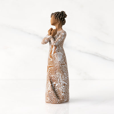 Willow Tree Music Speaks figurine with darker skin wearing a dress carved with musical symbols and dancing figures.