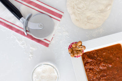 Nora Fleming mini bread basket with loaves wrapped in a red gingham napkin; cozy table accent for seasonal gatherings 