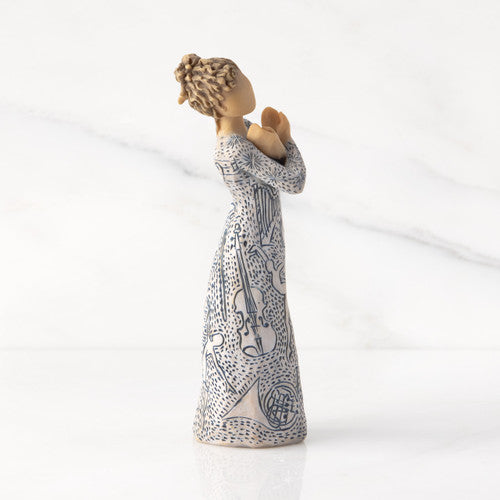 Willow Tree Music Speaks figurine with lighter skin featuring a dress carved with musical symbols and dancing figures.