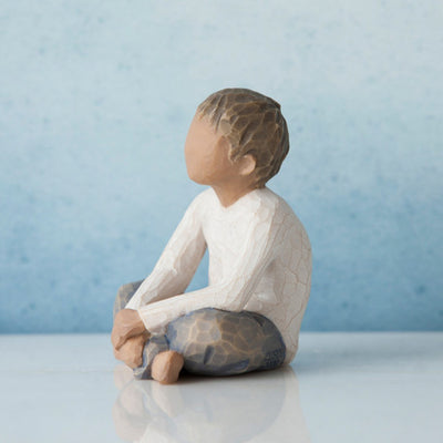 Willow Tree Imaginative Child figurine of seated boy with darker skin tone and hair.