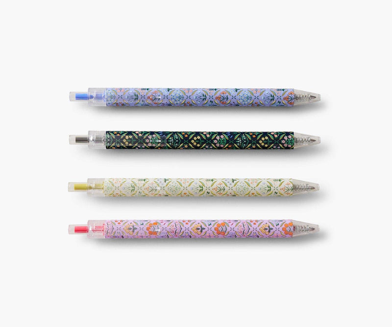 Set of four Rifle Paper Co. Estee gel pens with floral designs and colored inks in blue, black, red, and metallic gold.