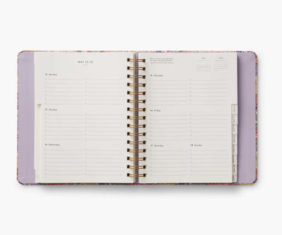 Rifle Paper Co. Mimi 2024–2025 planner with floral cover, gold foil accents, weekly and monthly views, stickers, and storage folders.
