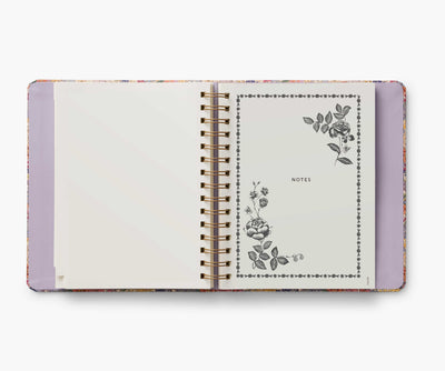 Rifle Paper Co. Mimi 2024–2025 planner with floral cover, gold foil accents, weekly and monthly views, stickers, and storage folders.
