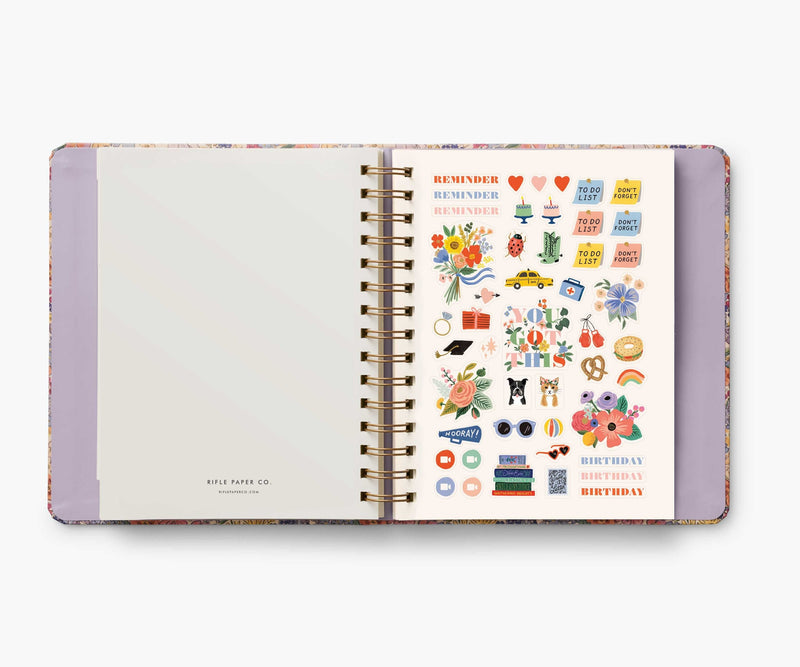 Rifle Paper Co. Mimi 2024–2025 planner with floral cover, gold foil accents, weekly and monthly views, stickers, and storage folders.
