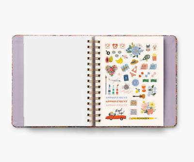 Rifle Paper Co. Mimi 2024–2025 planner with floral cover, gold foil accents, weekly and monthly views, stickers, and storage folders.