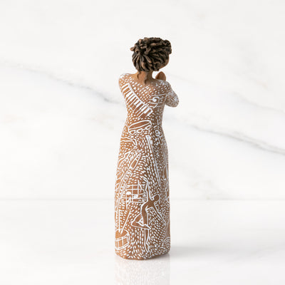 Willow Tree Music Speaks figurine with darker skin wearing a dress carved with musical symbols and dancing figures.