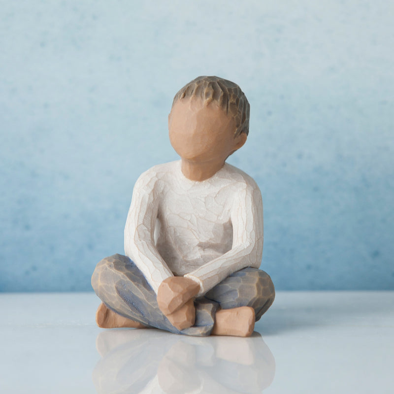 Willow Tree Imaginative Child figurine of seated boy with darker skin tone and hair.