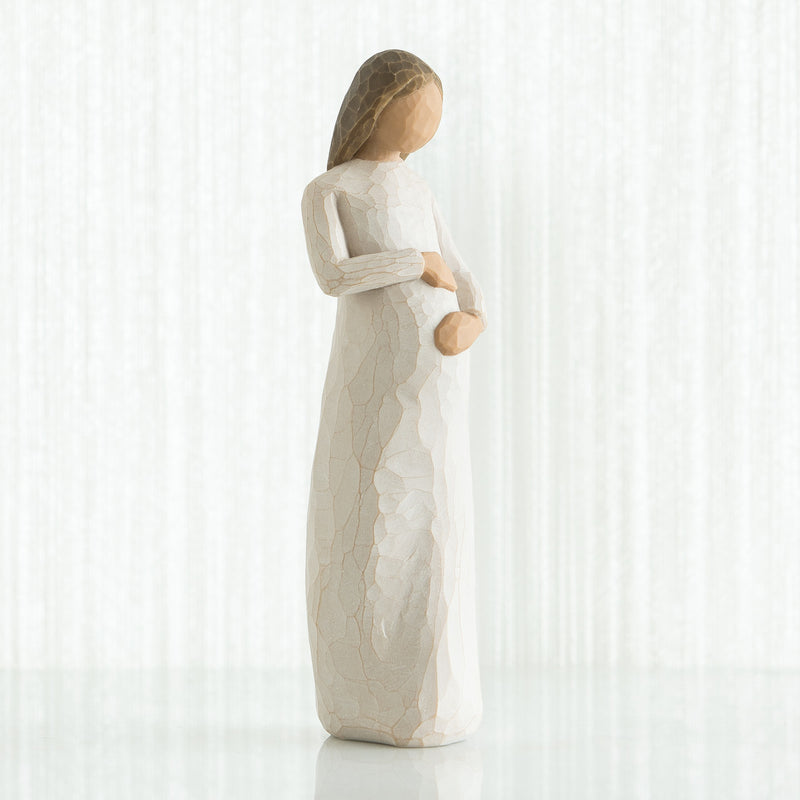 Willow Tree Cherish figurine of pregnant woman in cream dress with hands on belly.