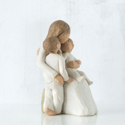 Willow Tree Quietly figurine of mother seated with toddler in arms and older child standing beside her, all in cream outfits.