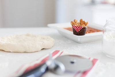 Nora Fleming mini bread basket with loaves wrapped in a red gingham napkin; cozy table accent for seasonal gatherings 