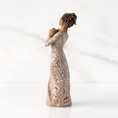 Willow Tree Music Speaks figurine with darker skin wearing a dress carved with musical symbols and dancing figures.