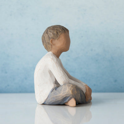 Willow Tree Imaginative Child figurine of seated boy with darker skin tone and hair.