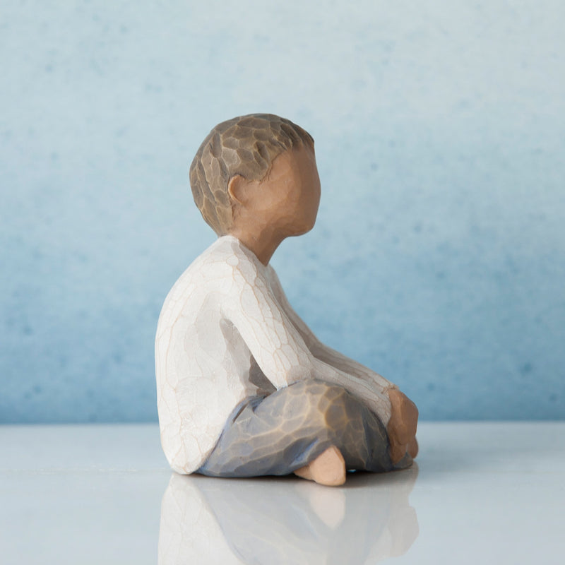 Willow Tree Imaginative Child figurine of seated boy with darker skin tone and hair.