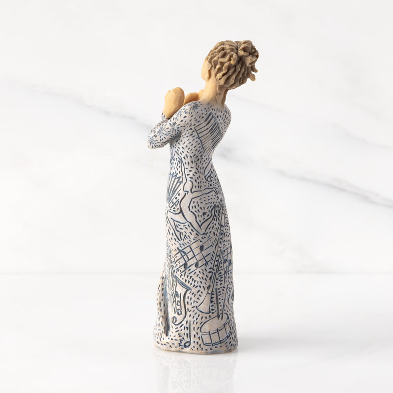 Willow Tree Music Speaks figurine with lighter skin featuring a dress carved with musical symbols and dancing figures.