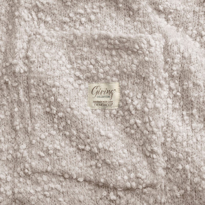 Ivory-colored soft giving shawl with a knitted texture, packaged for gifting, designed to provide comfort and warmth.