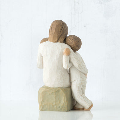 Willow Tree Quietly figurine of mother seated with toddler in arms and older child standing beside her, all in cream outfits.