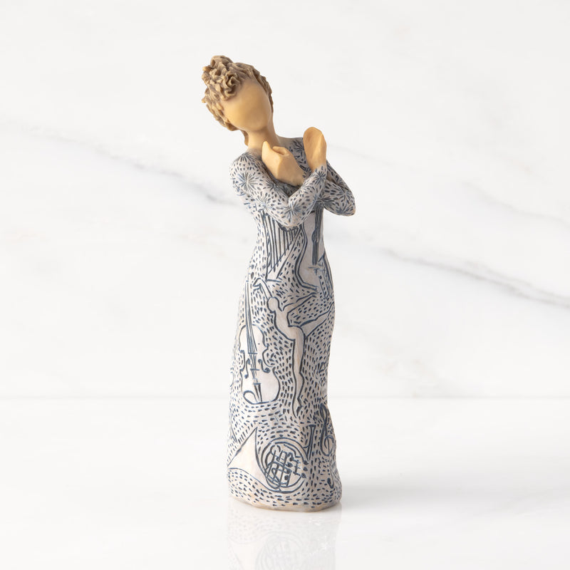 Willow Tree Music Speaks figurine with lighter skin featuring a dress carved with musical symbols and dancing figures.