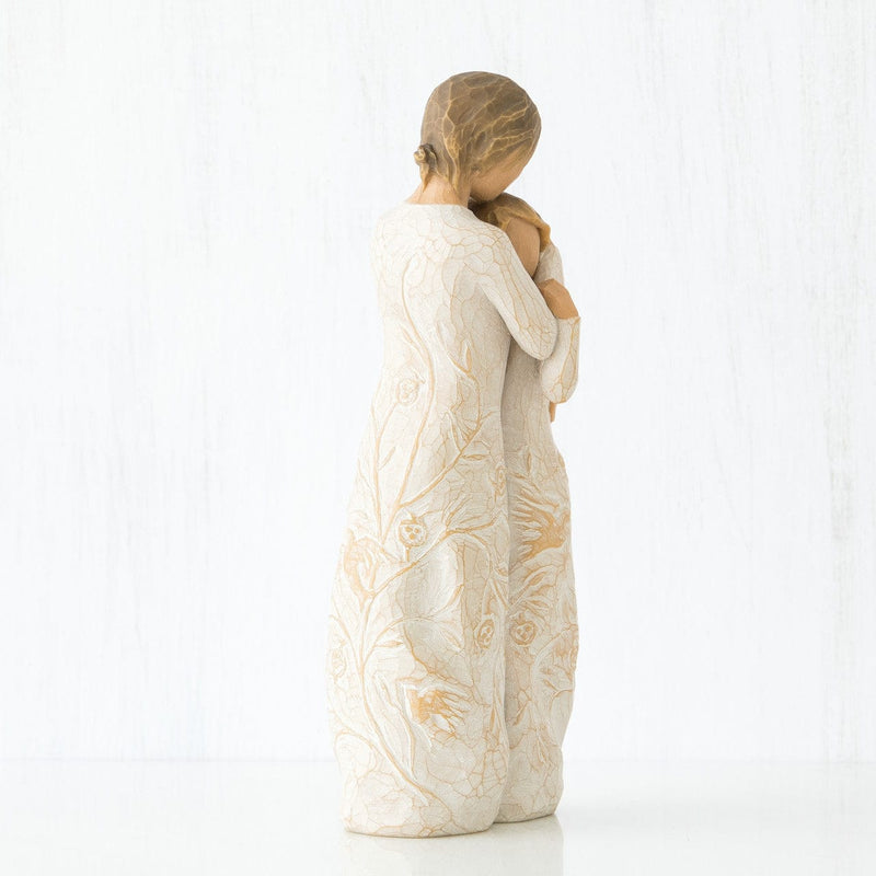 Close to me: a willow tree with a standing woman embracing a younger girl, both in cream dresses carved with intertwined vines and leaves.