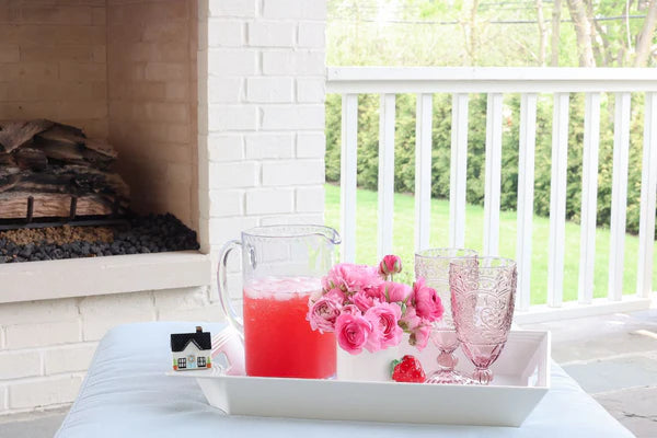 Watermelon juice pitcher with ice cubes on a white Nora Fleming rectangular tray 