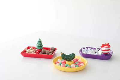 Three colorful ceramic trays filled with candy and nuts
