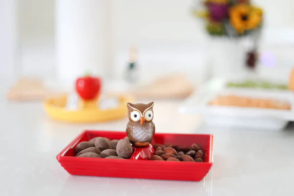 Three colorful ceramic trays filled with candy and nuts