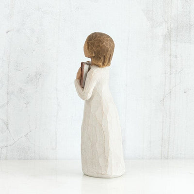 The figurine features a young girl sitting with a book open in her lap.