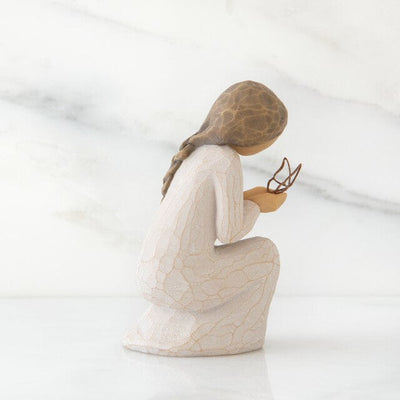 hand-painted resin figure in cream dress, kneeling with a gold leaf wire butterfly alighted